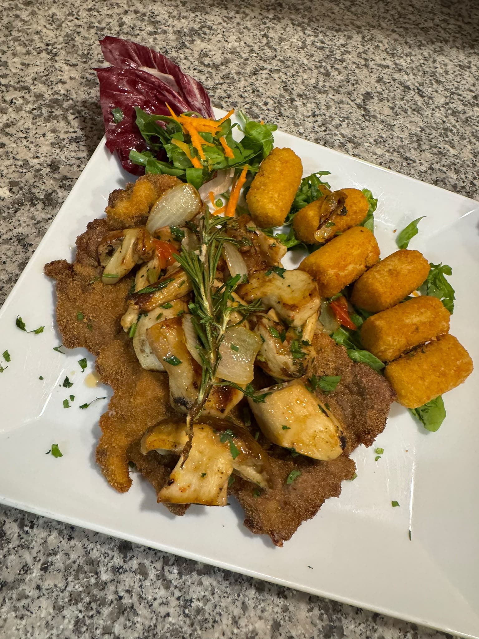 Paniertes Schnitzel mit gebratenen Pilzen, Rosmarin und Kroketten