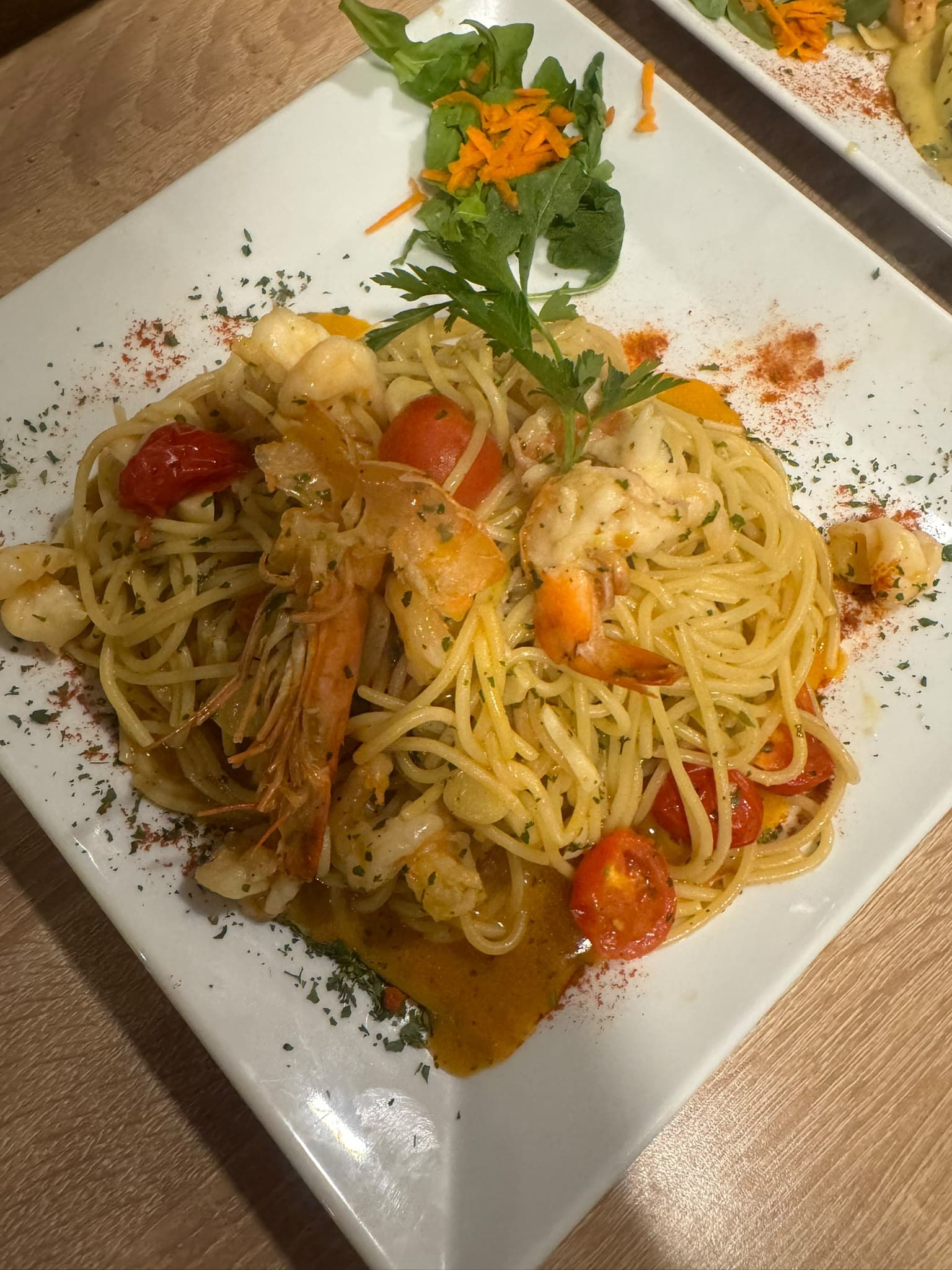 Spaghetti mit Garnelen und Kirschtomaten auf einem weißen Teller
